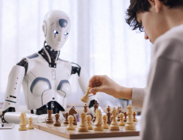The boy's determination shows as he plays chess with a robot.